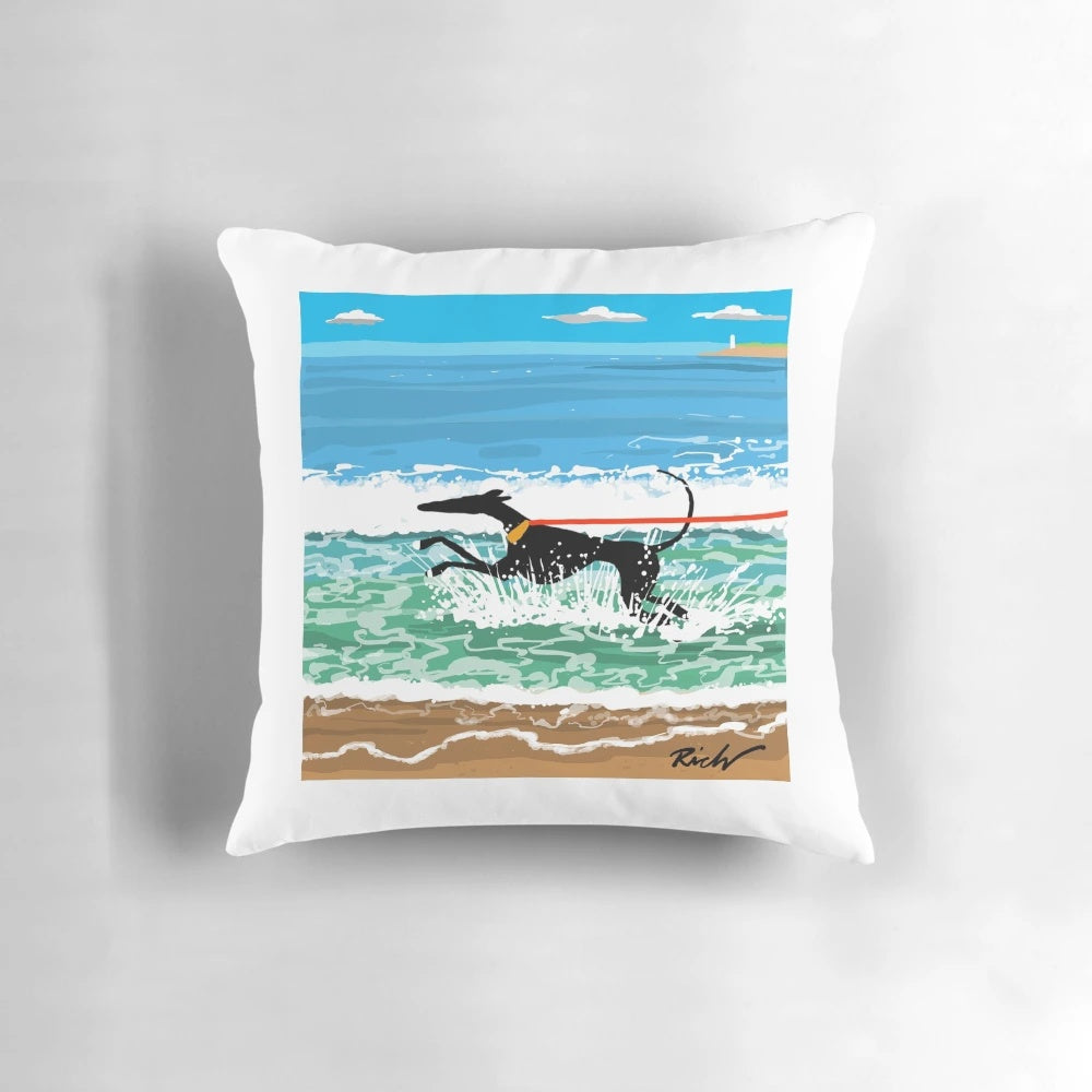 Image of a decorative pillow featuring a coastal landscape with greyhounds, whippets, and lurchers