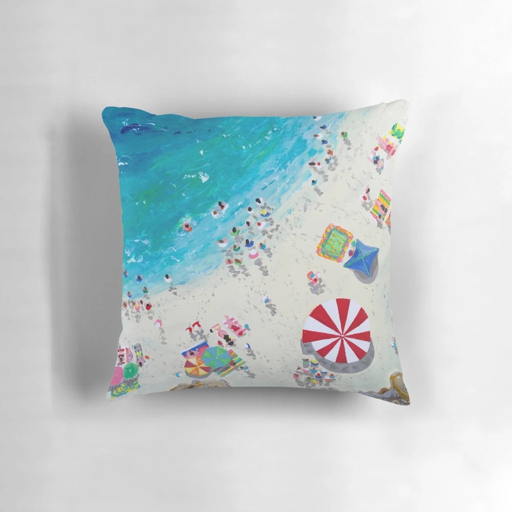 Coastal-inspired pillow featuring an aerial view of a beach and waves, designed by artist Stephanie Fuller