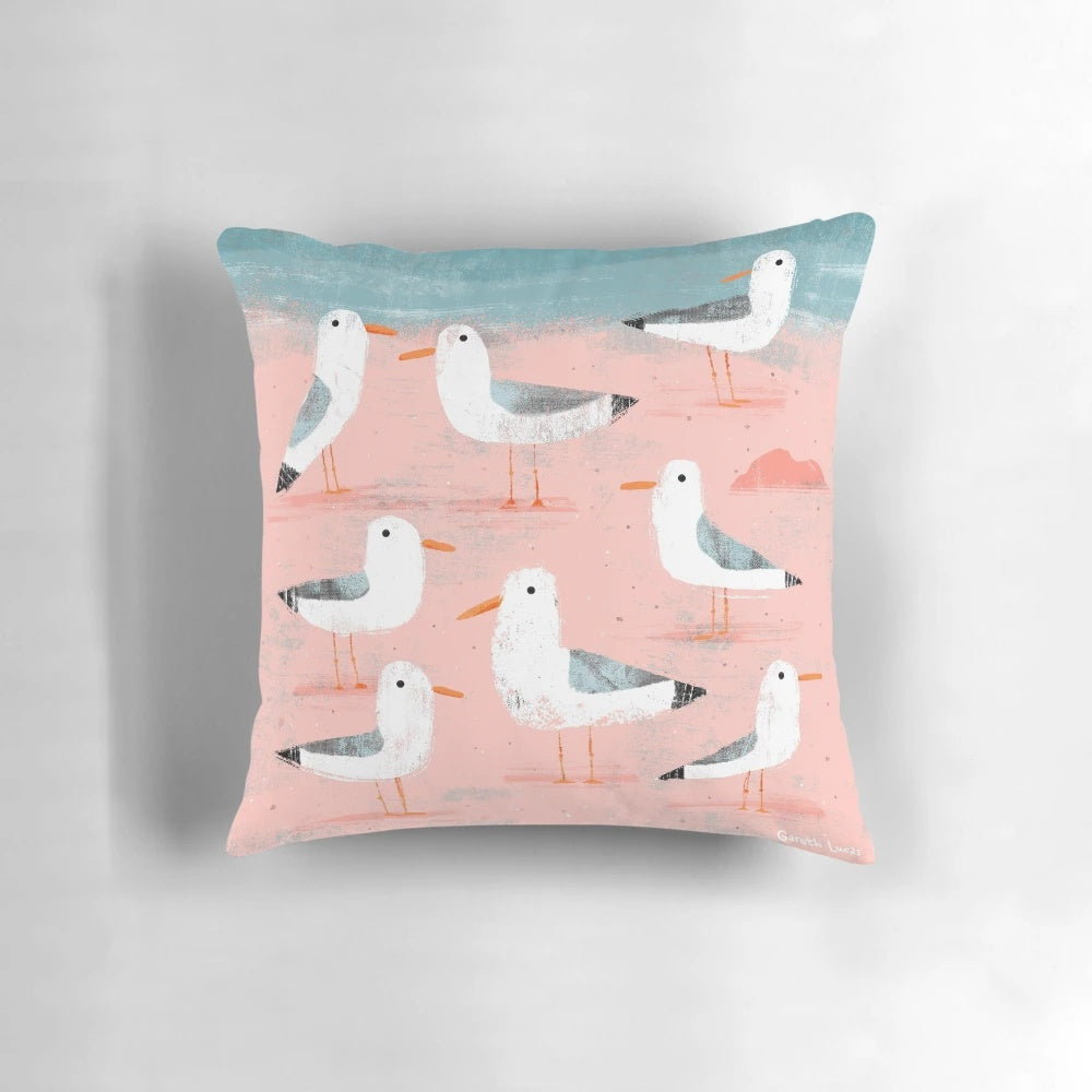 Digital illustration of seagulls flying over a coastal beach scene, used as a decorative throw pillow.