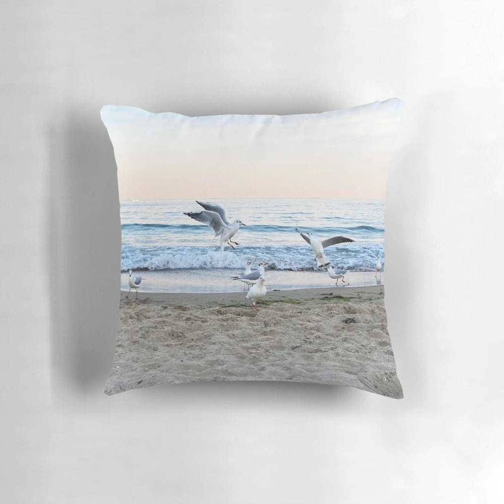 Decorative throw pillow featuring a scenic image of seagulls sitting on the beach