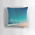 Colorful coastal art pillow depicting ocean waves, a surfer, and a teal and rose landscape for beach house decor.