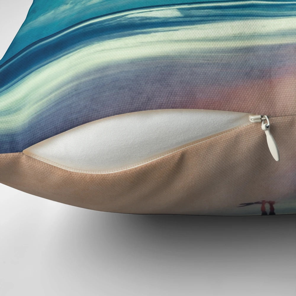 Colorful coastal art pillow depicting ocean waves, a surfer, and a teal and rose landscape for beach house decor.