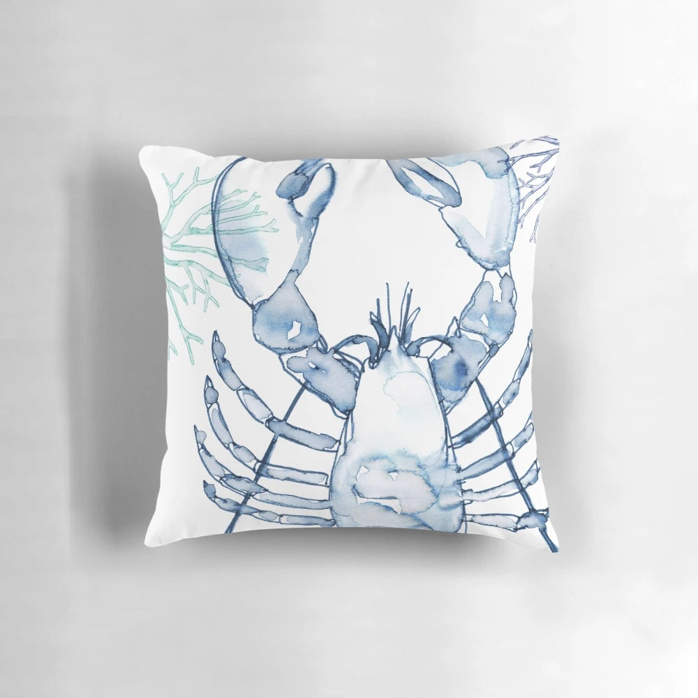 A watercolor painting of a coastal lobster in shades of blue and white, featured on a decorative throw pillow.