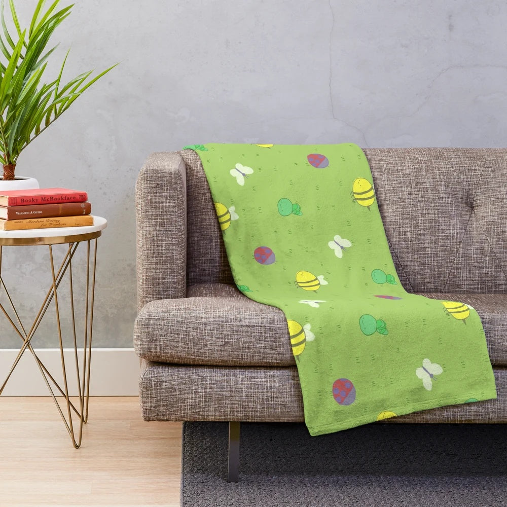Colorful plush blanket featuring an adventure-inspired pattern with birds, bees, caterpillars, and other cute insects and critters