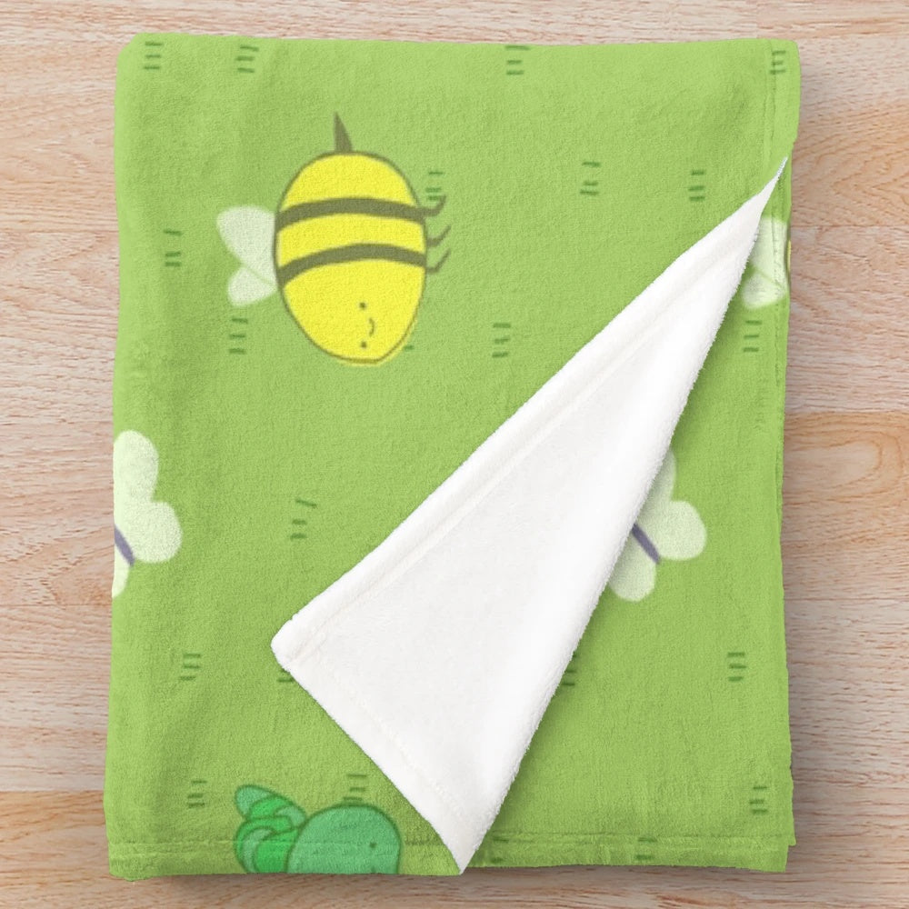 Colorful plush blanket featuring an adventure-inspired pattern with birds, bees, caterpillars, and other cute insects and critters