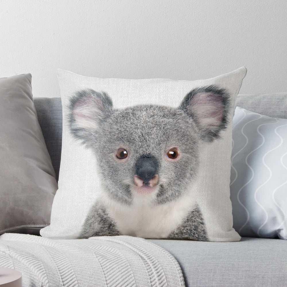 A colorful and whimsical pillow featuring a portrait of a baby koala bear against a nature-inspired backdrop.