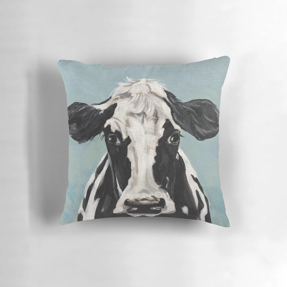 A vibrant black and white cow painting on a decorative throw pillow for farmhouse-style living spaces.