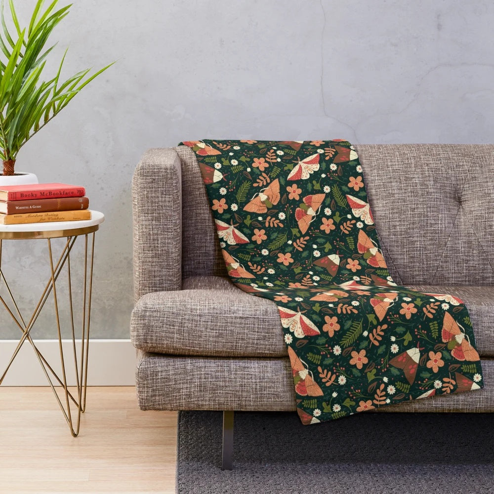 Colorful plush blanket with a pattern featuring moths, leaves, and flowers