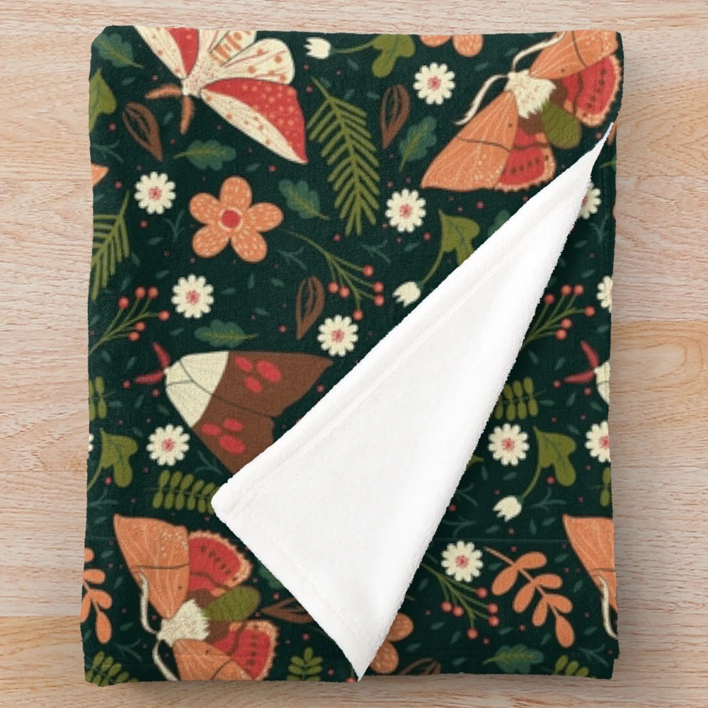Colorful plush blanket with a pattern featuring moths, leaves, and flowers