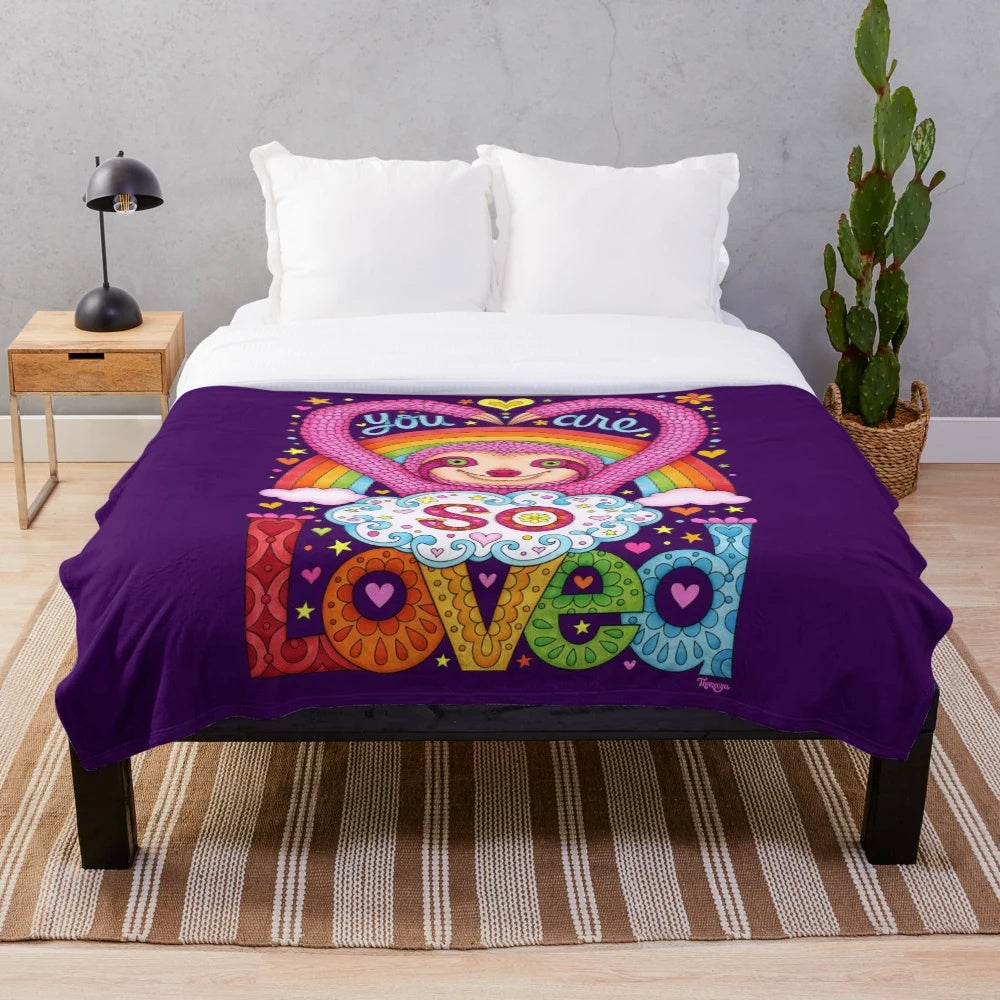 Colorful rainbow sloth plush blanket with a happy, smiling sloth design