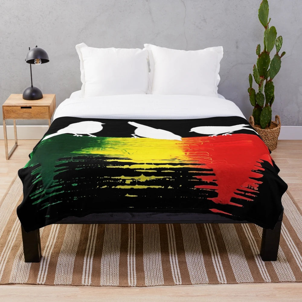 Plush blanket featuring three little birds in rasta colors of red, green, and gold