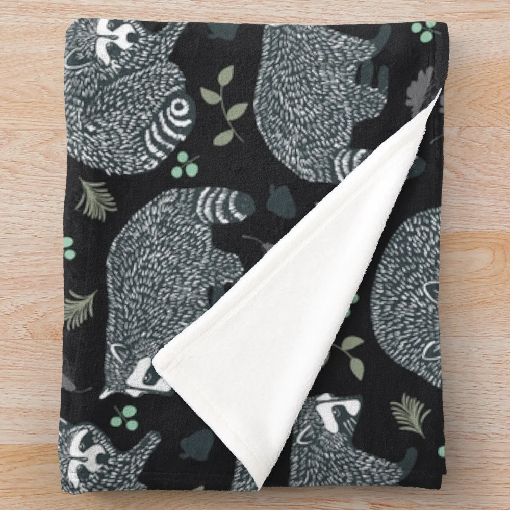 Soft and warm plush blanket featuring a repeating raccoon pattern design