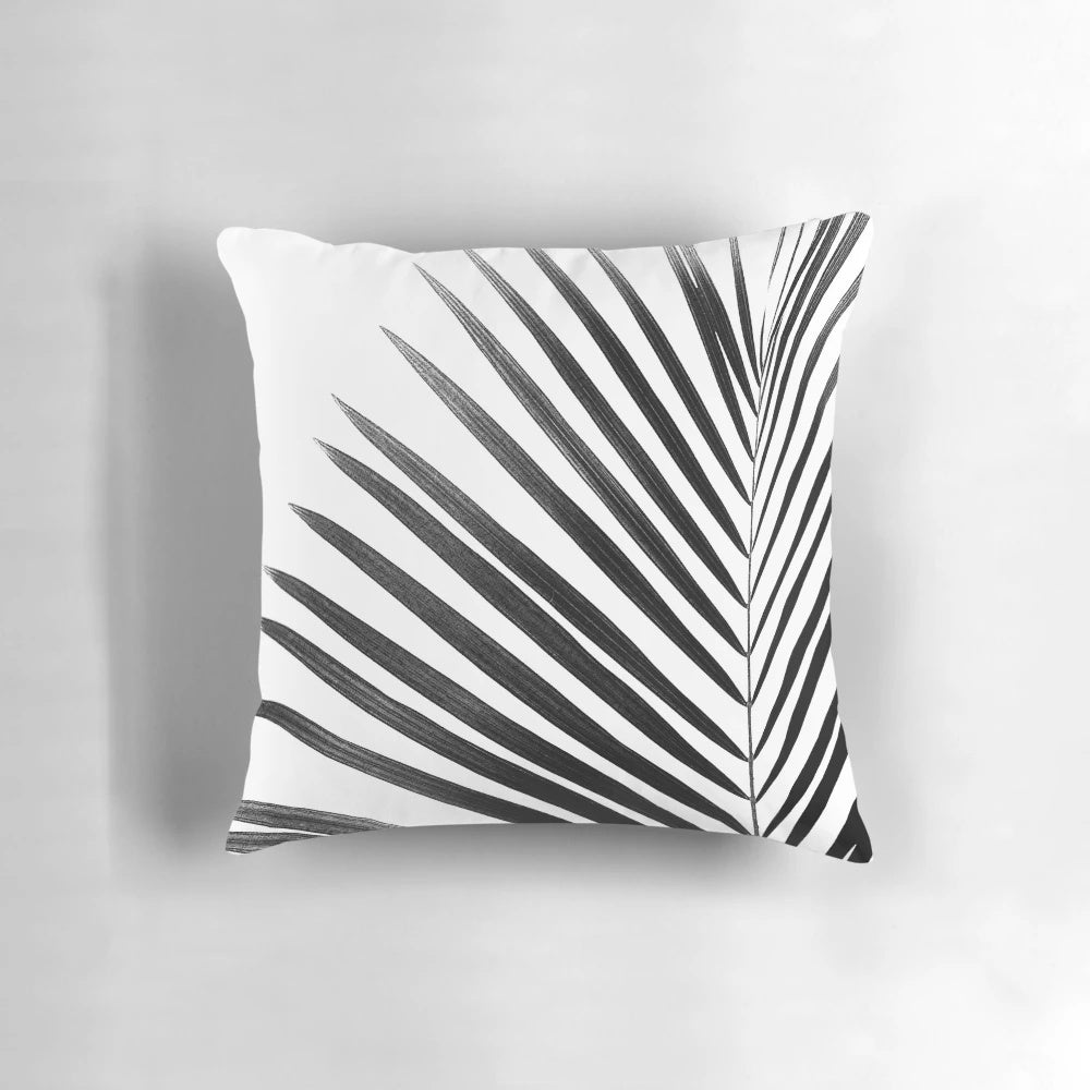 A modern black and white palm leaf design on a decorative throw pillow