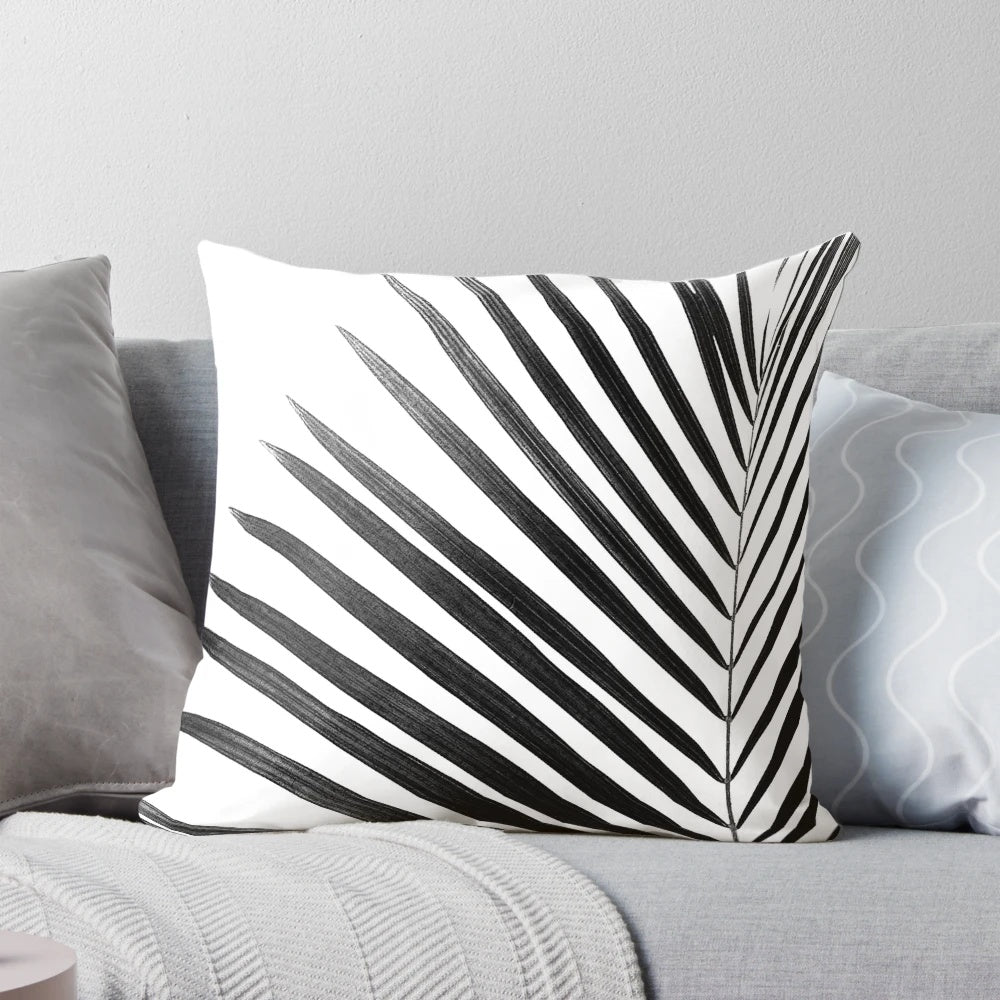 A modern black and white palm leaf design on a decorative throw pillow