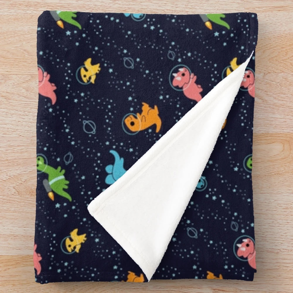 Cozy plush blanket featuring a pattern of dinosaurs in space with stars and galaxies