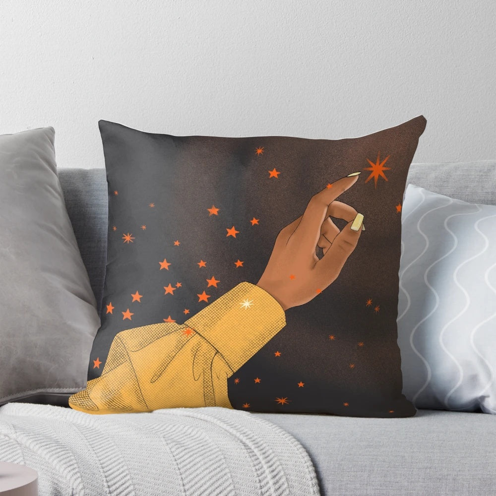 A pillow featuring a hand reaching for the stars against a cosmic, galaxy-inspired background, representing the empowerment of black women.