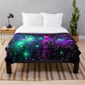 Cozy plush blanket featuring a vibrant cosmic nebula print in shades of mint, purple, and pink