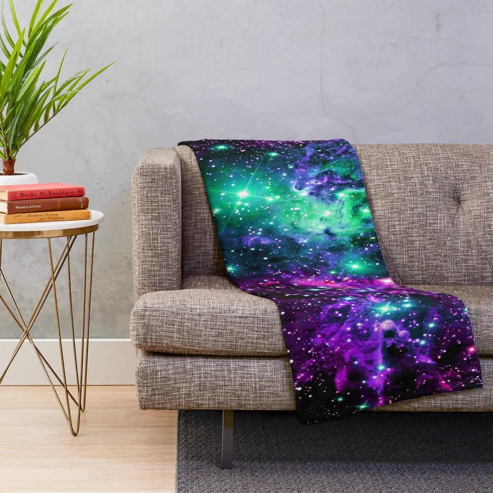 Cozy plush blanket featuring a vibrant cosmic nebula print in shades of mint, purple, and pink