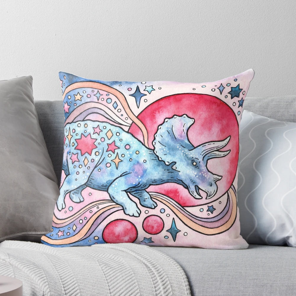 A watercolor illustration of a triceratops dinosaur against a starry, galactic backdrop on a plush, decorative pillow.