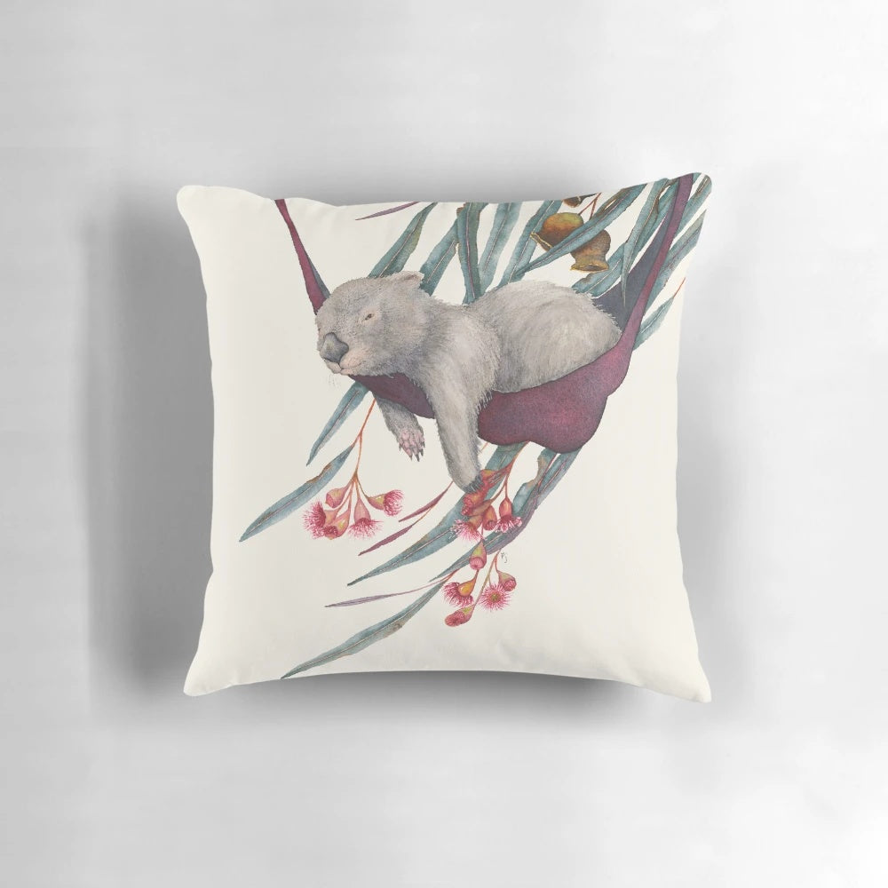 A soft, plush pillow featuring a cute, sleeping wombat in a watercolor painting design.