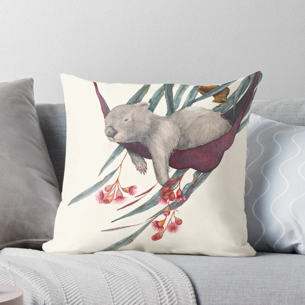 A soft, plush pillow featuring a cute, sleeping wombat in a watercolor painting design.