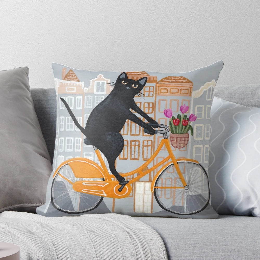 A cozy and whimsical throw pillow featuring a black cat riding an orange bicycle through the streets of Amsterdam.
