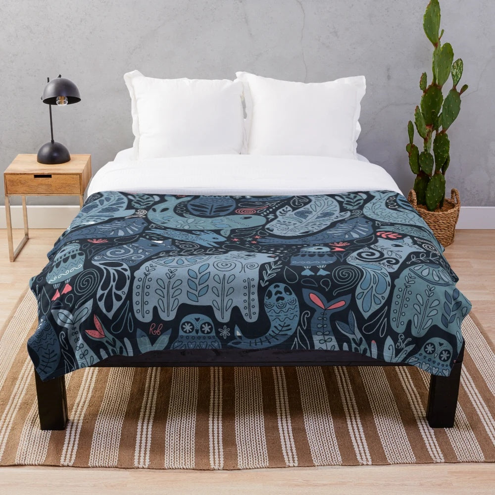 Plush blanket featuring illustrations of arctic animals including narwhal, polar bear, whale, puffin, owl, fox, bunny, and seal