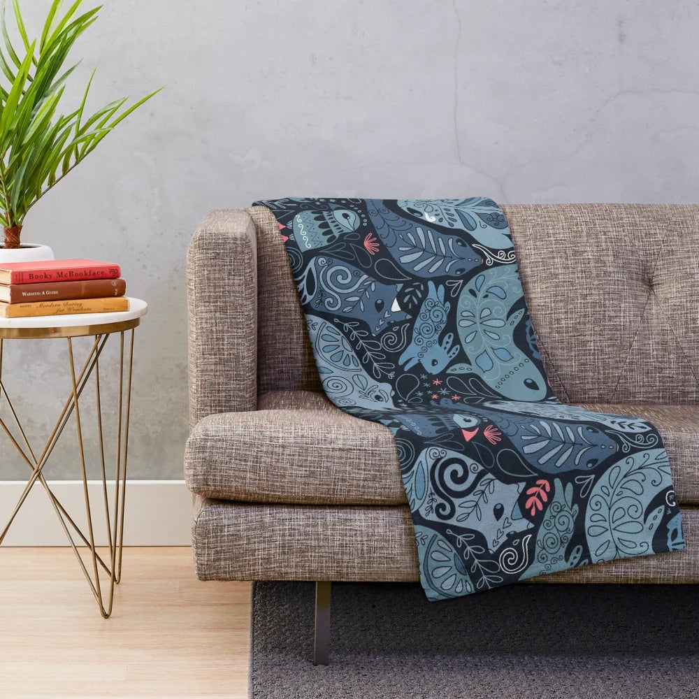 Plush blanket featuring illustrations of arctic animals including narwhal, polar bear, whale, puffin, owl, fox, bunny, and seal