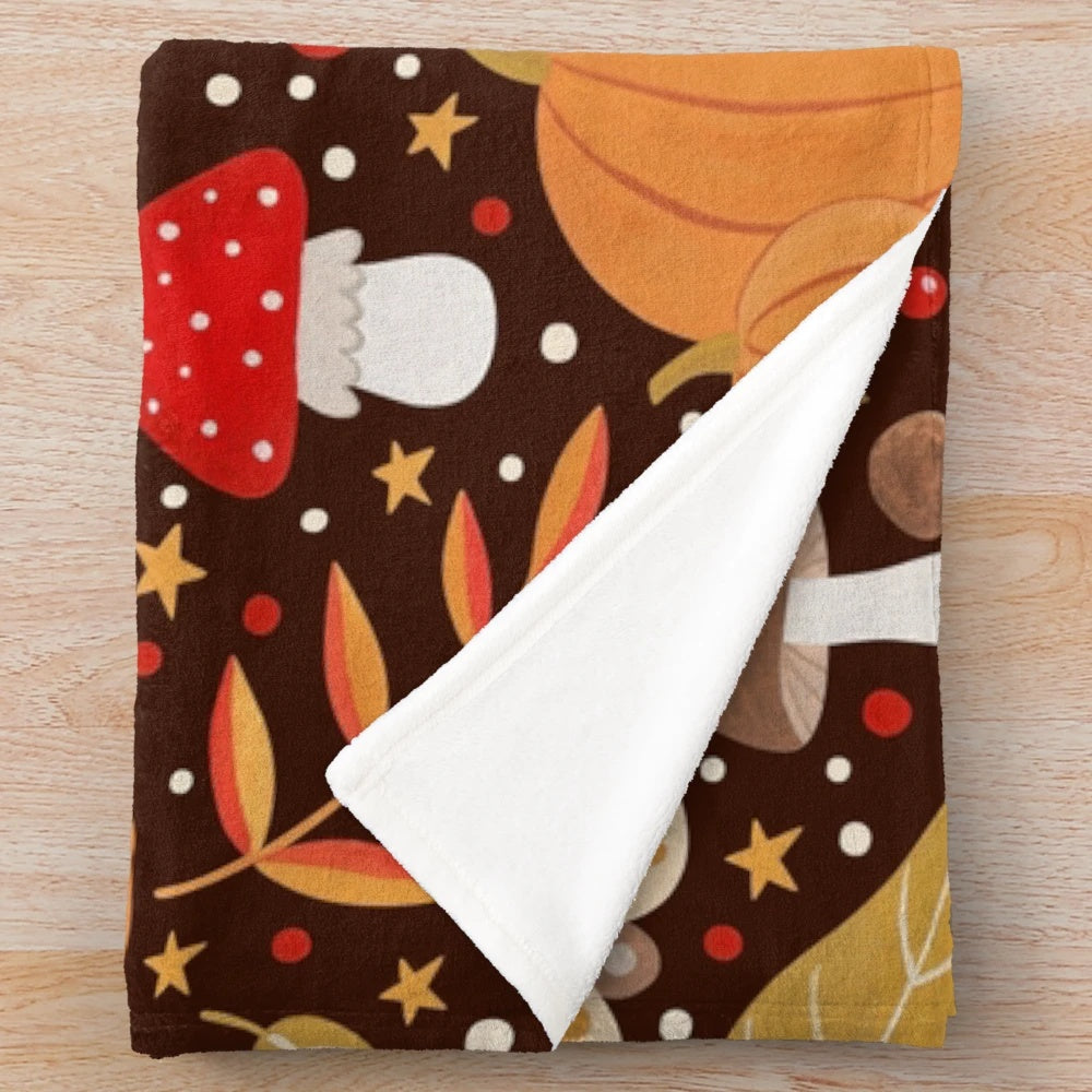 Autumn themed plush blanket with leaves, pumpkins, and other natural elements