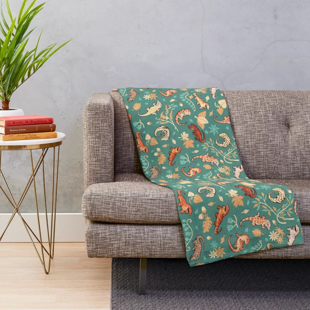 Plush blanket featuring a green gecko or lizard pattern in autumn colors