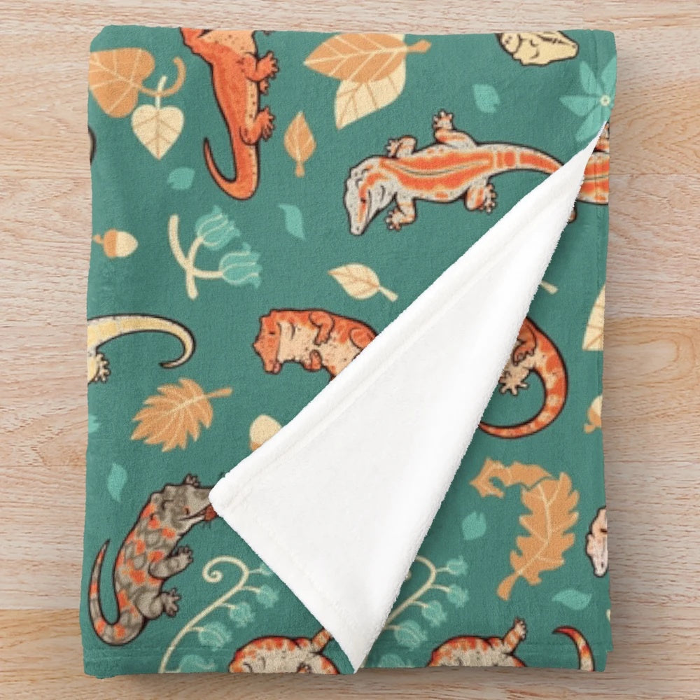 Plush blanket featuring a green gecko or lizard pattern in autumn colors