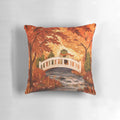 A plush, fall-themed pillow featuring a charming illustration of a frog sitting on a bridge surrounded by vibrant autumn leaves.