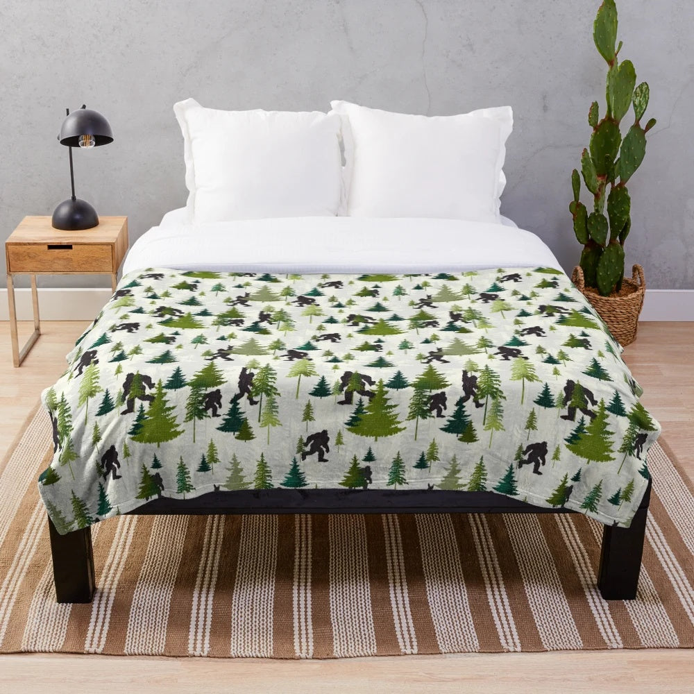 A plush blanket featuring a Bigfoot design, perfect for outdoor adventures and nature enthusiasts.