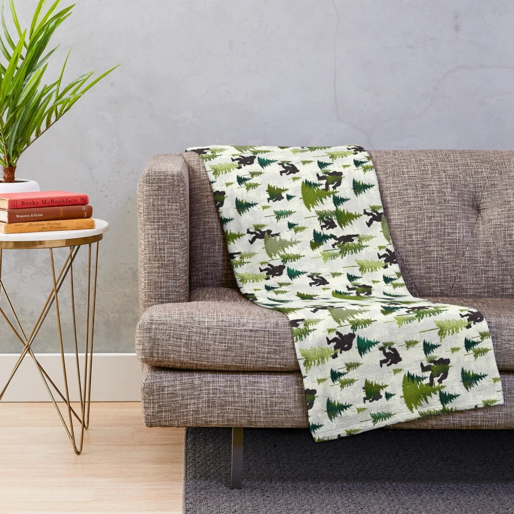 A plush blanket featuring a Bigfoot design, perfect for outdoor adventures and nature enthusiasts.