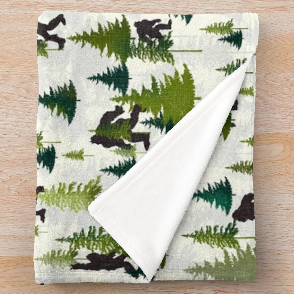 A plush blanket featuring a Bigfoot design, perfect for outdoor adventures and nature enthusiasts.