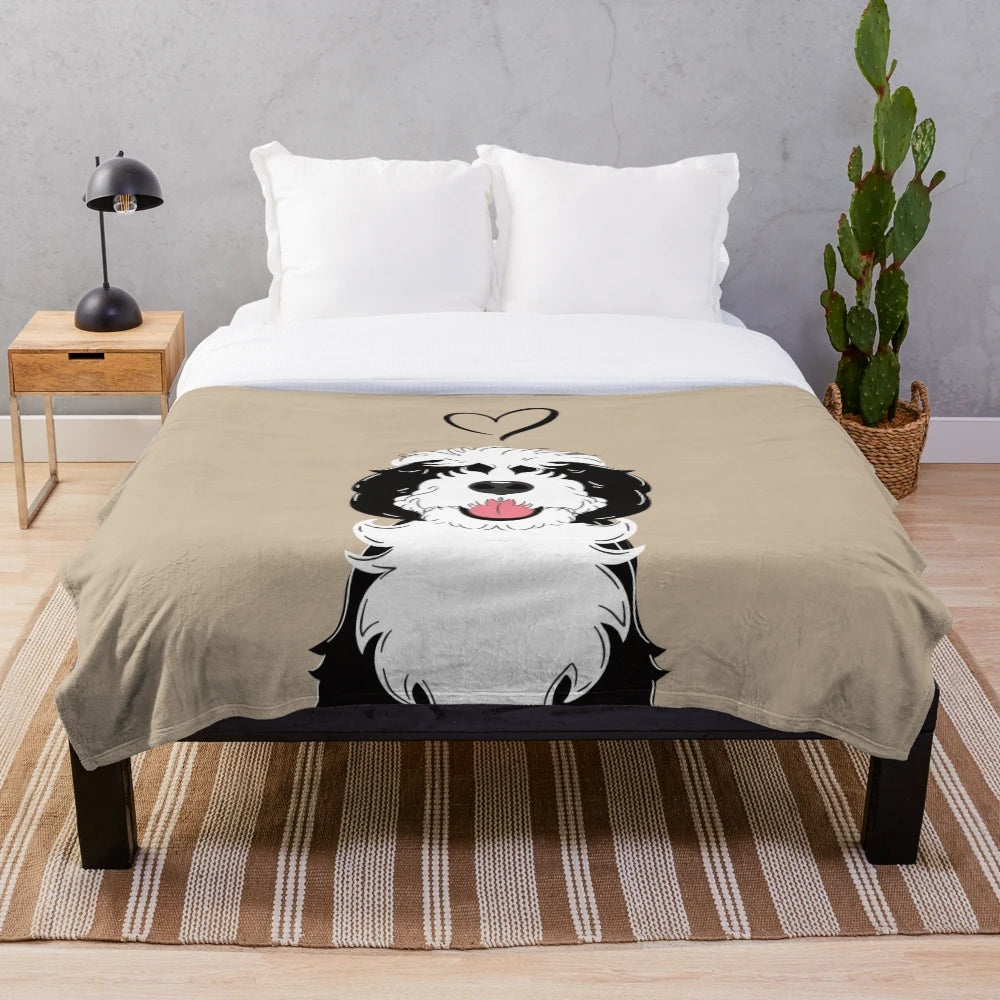 Black and white sheepadoodle dog on a plush blanket