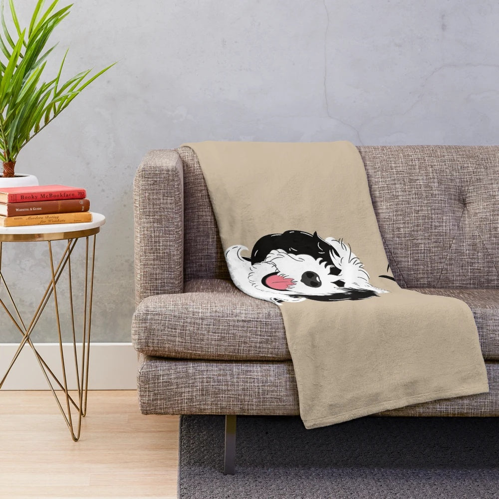 Black and white sheepadoodle dog on a plush blanket