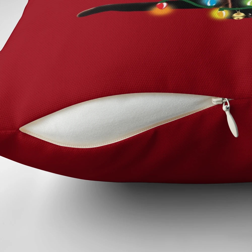 A black cat tangled up in Christmas tree lights, sitting on a festive holiday pillow with a Santa hat.