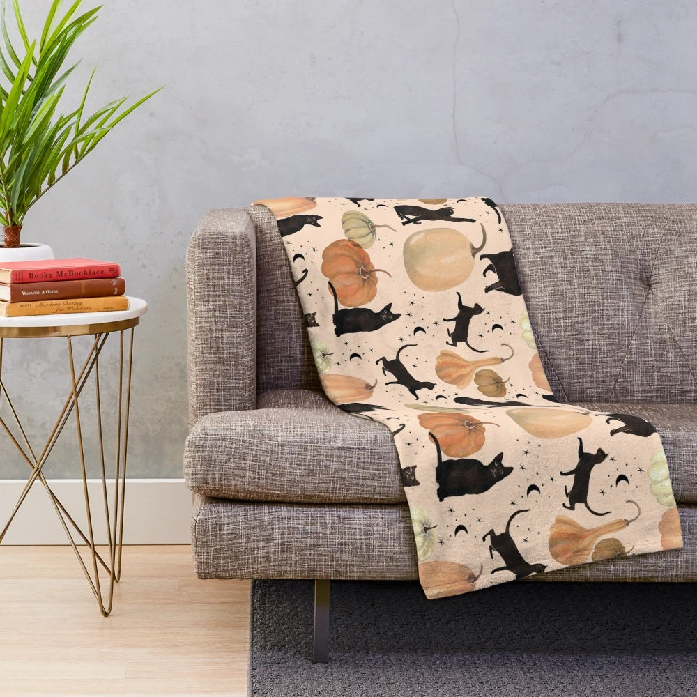 Plush throw blanket featuring a watercolor pattern of black cats and pumpkins for fall and Halloween