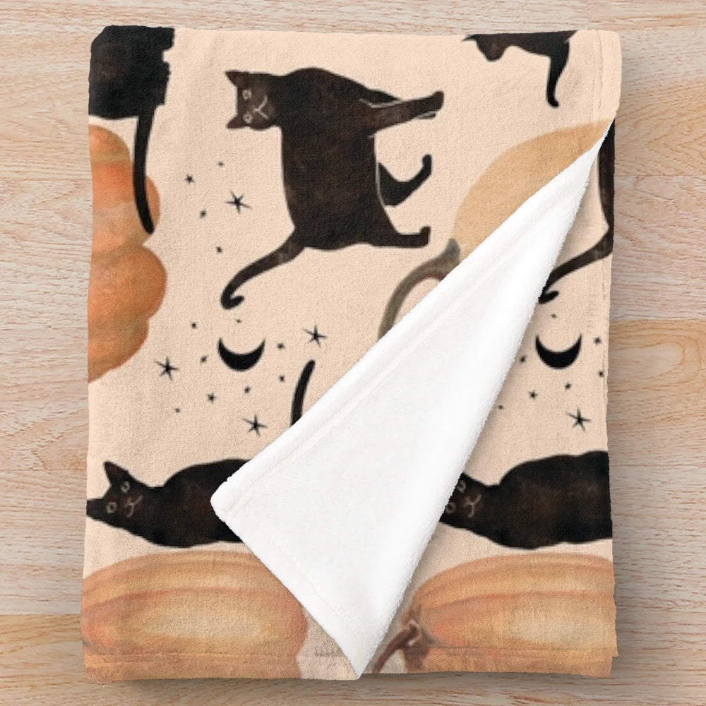 Plush throw blanket featuring a watercolor pattern of black cats and pumpkins for fall and Halloween