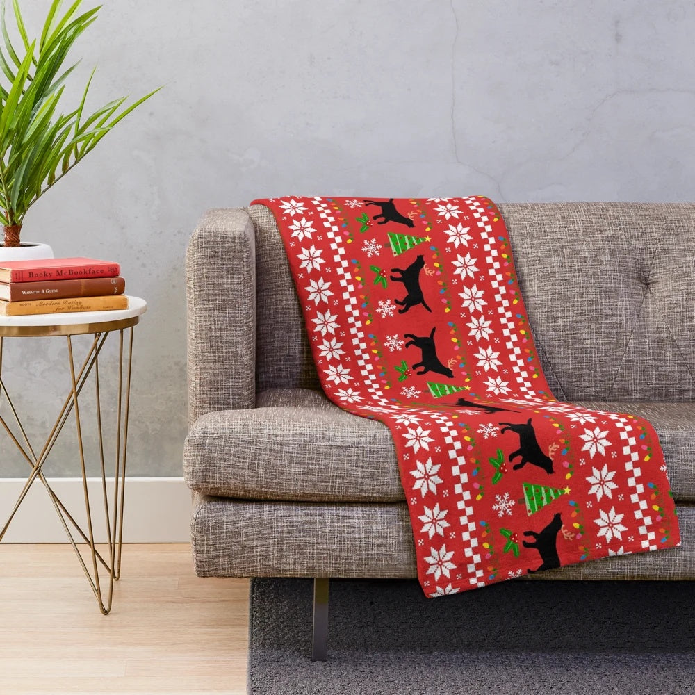 Black labrador retriever wearing reindeer antlers on a plush Christmas blanket