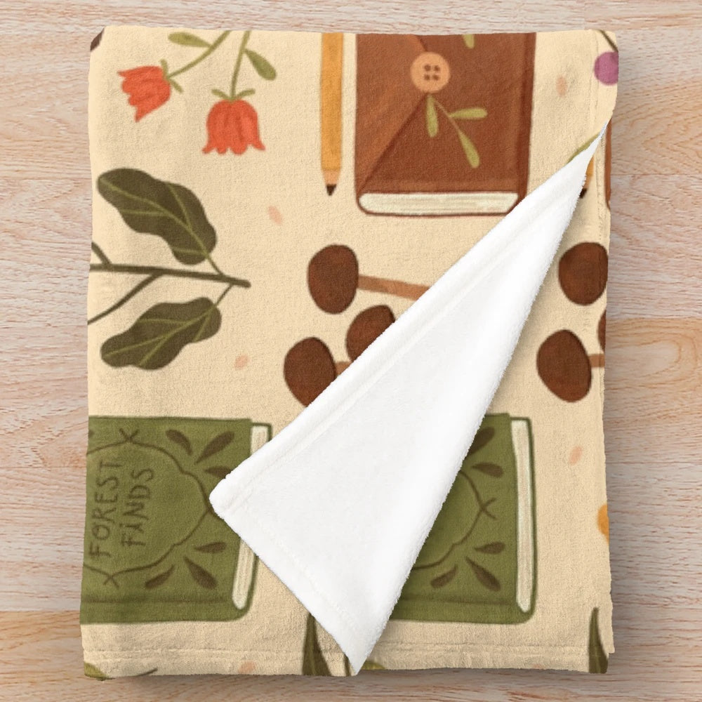 Plush blanket with a bookish forest and botanical pattern