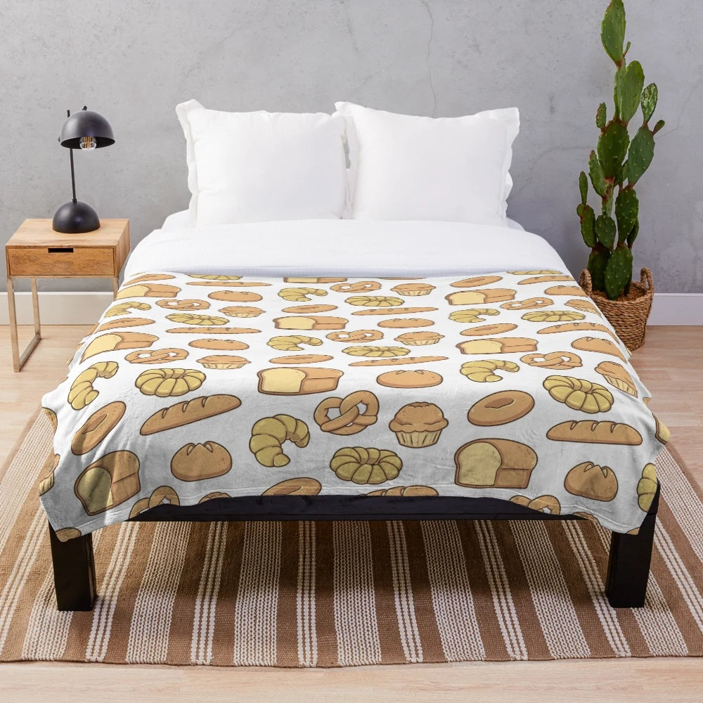 Plush blanket featuring an assortment of bread designs including baguettes, croissants, and loaves of bread