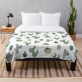 Cozy plush blanket featuring a repeating pattern of sloths and cacti in green and white