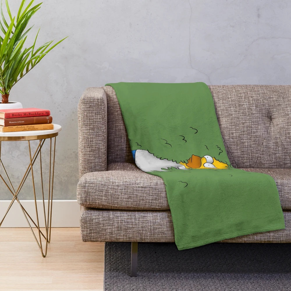 Homer Simpson cartoon character peeking out from bushes on a plush blanket