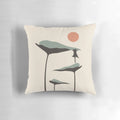 A decorative throw pillow featuring a black cat and lush green plants against a vibrant sunset landscape.