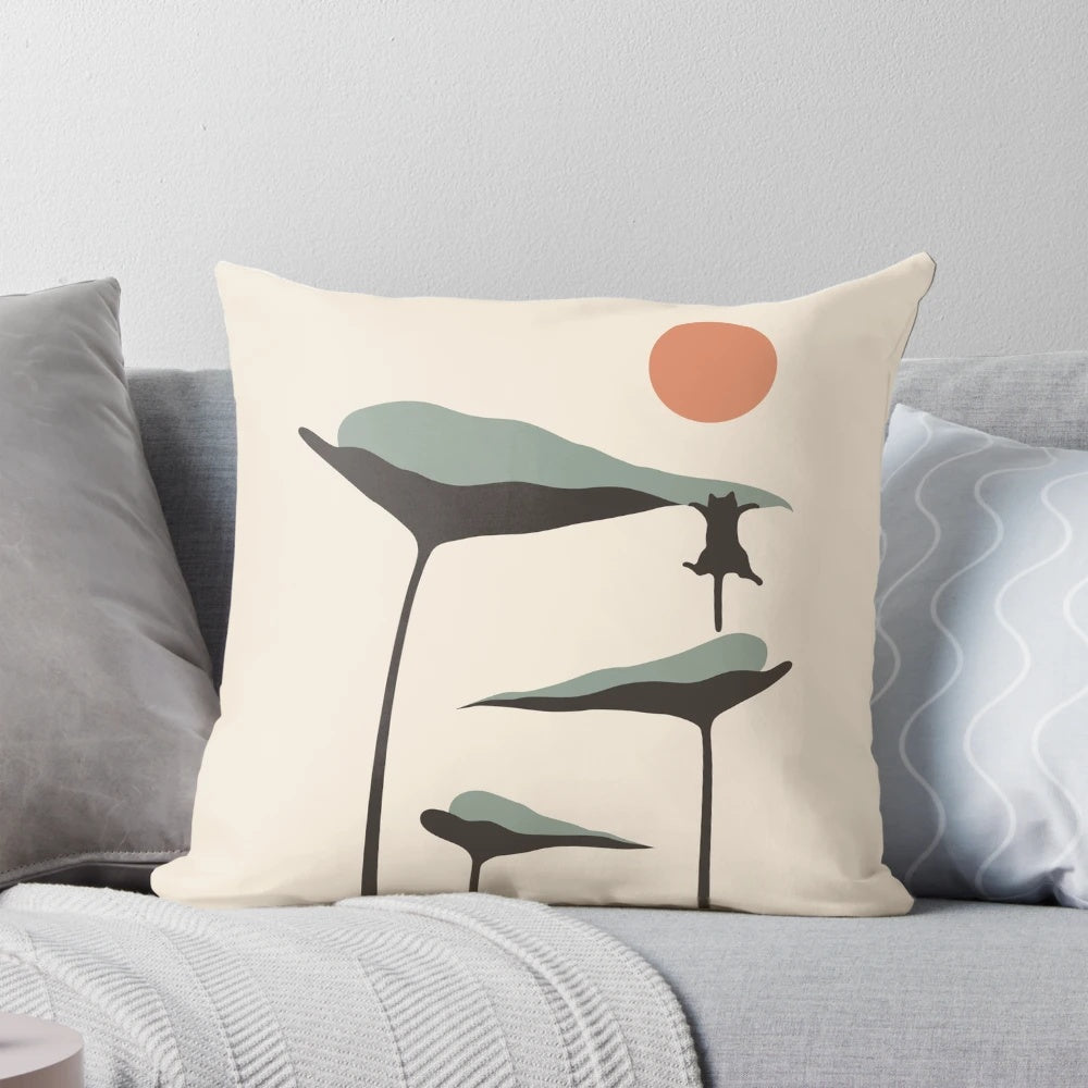 A decorative throw pillow featuring a black cat and lush green plants against a vibrant sunset landscape.