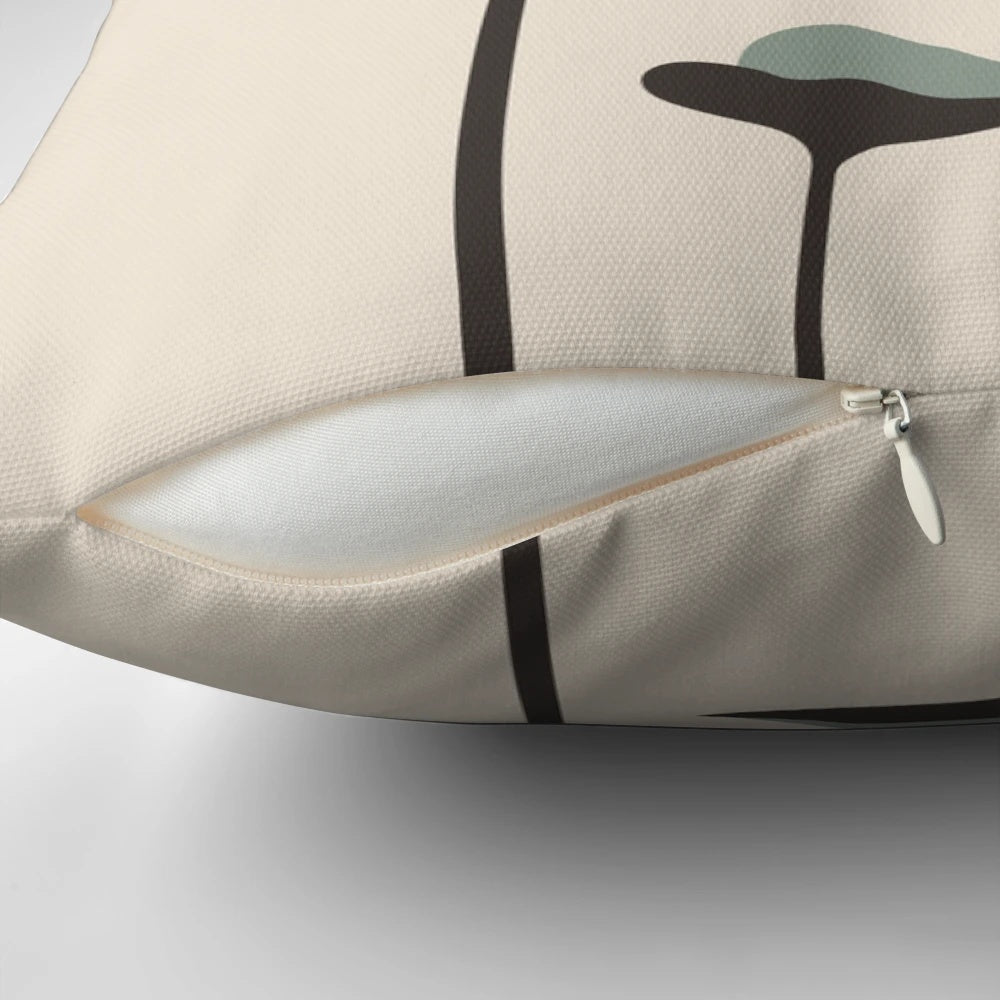 A decorative throw pillow featuring a black cat and lush green plants against a vibrant sunset landscape.