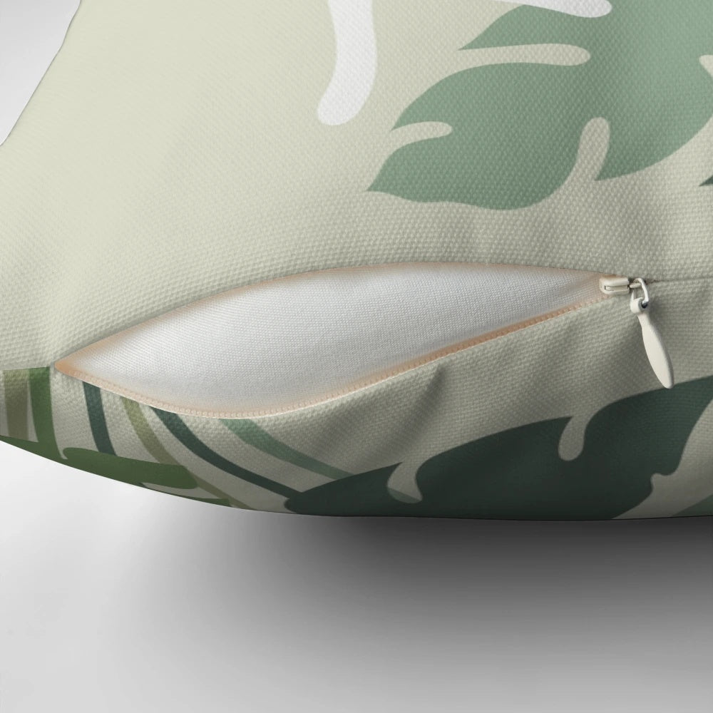 A cozy pillow featuring a cat resting next to a lush, green plant in a nature-inspired setting