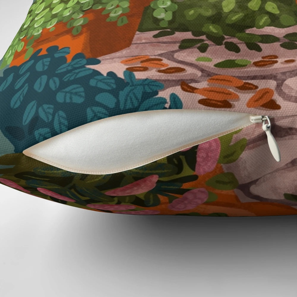 A whimsical pillow featuring a cat sitting in a garden with flowers and plants